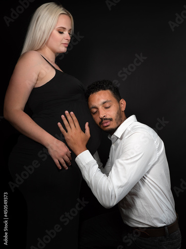 Profile view of a stylish and happy multi-ethnic couple expecting a baby