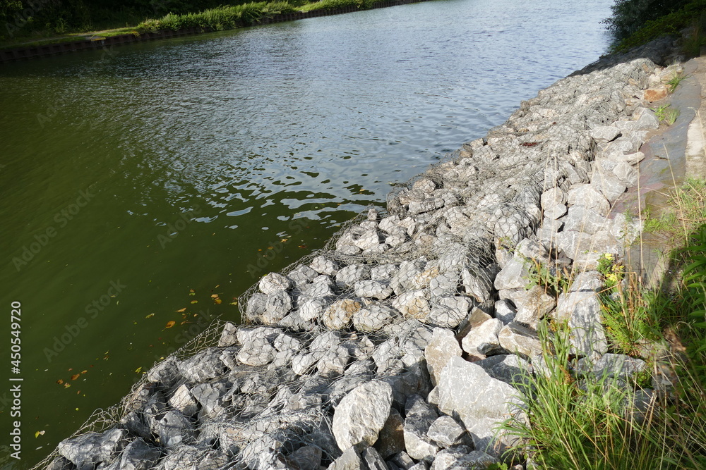 Slope stabilization of an artificial waterway Midland Canal (Mittellandkanal) in Germany by using natural stones and wire mesh. Hannover, Lower Saxony, Germany.
