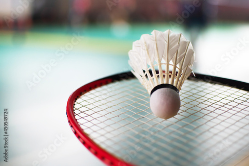 White shuttlecock on badminton racket, blurred badminton court background, concept for badminton lovers around the world. © Sophon_Nawit