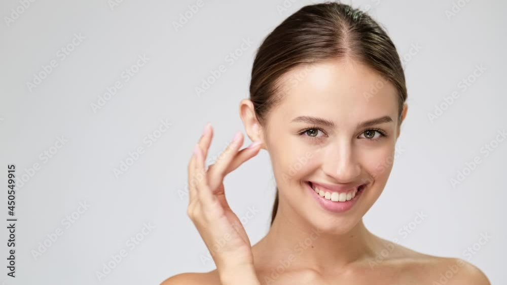 Beautiful Young Woman with Clean Fresh Skin standing over light grey background Beautiful Young Woman with Clean Fresh Skin standing over light grey background