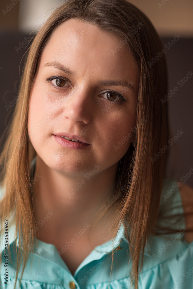 Portrait of a young beautiful brown-haired woman with long hair indoors on a dark background. Portrait of a young beautiful brown-haired woman with long hair indoors on a dark background.