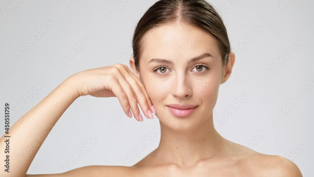 Beautiful Young Woman with Clean Fresh Skin standing over light grey background Beautiful Young Woman with Clean Fresh Skin standing over light grey background