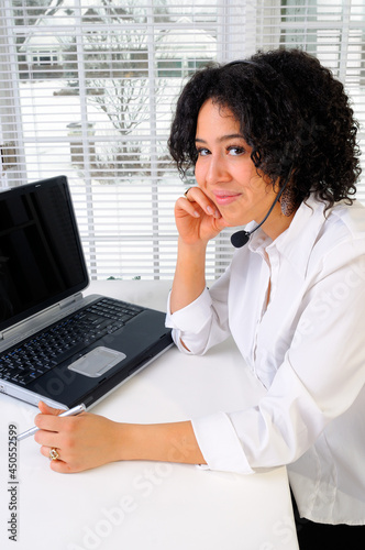 Beautiful Mixed Race Young Woman Sat At Her Desk In An Office With Laptop Computer Call Center