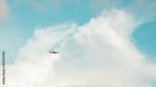 An Airplane flying high in blue sky across the cottony cloud.