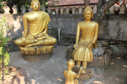 golden statues of buddha in a temple (wat choumkhong) in luang prabang (laos)  photo