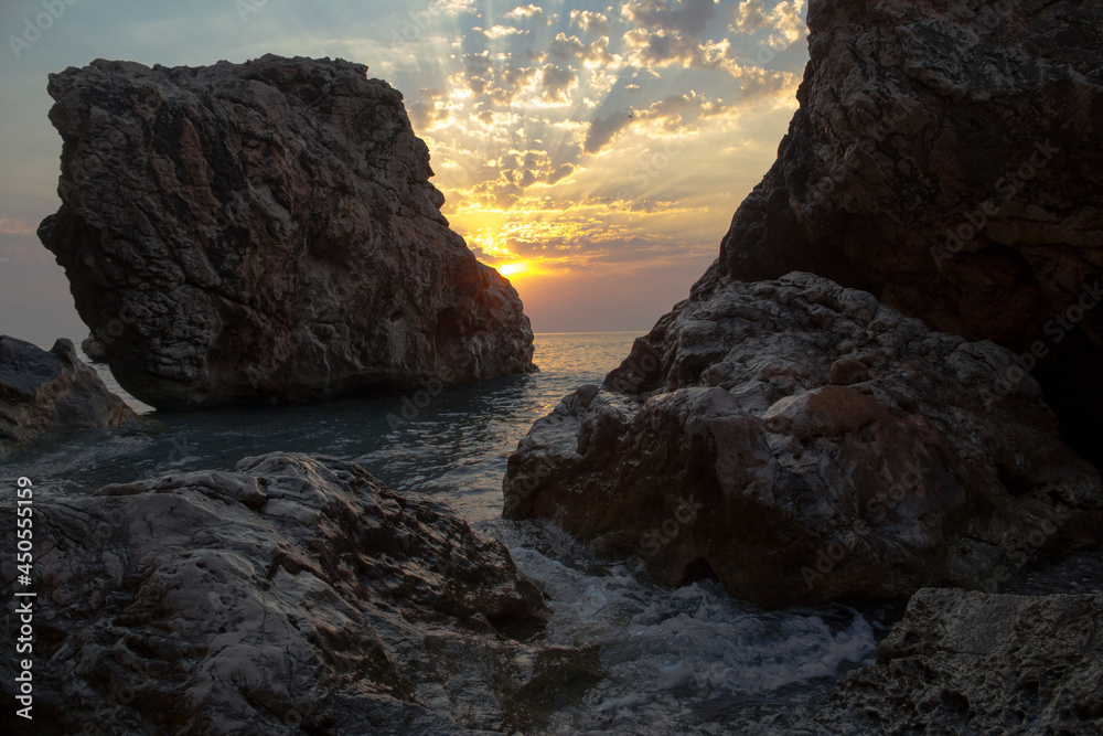 Coastal rocks at sunset. Rocky coast with waves. Coastal rocks at sunset. Rocky coast with waves.