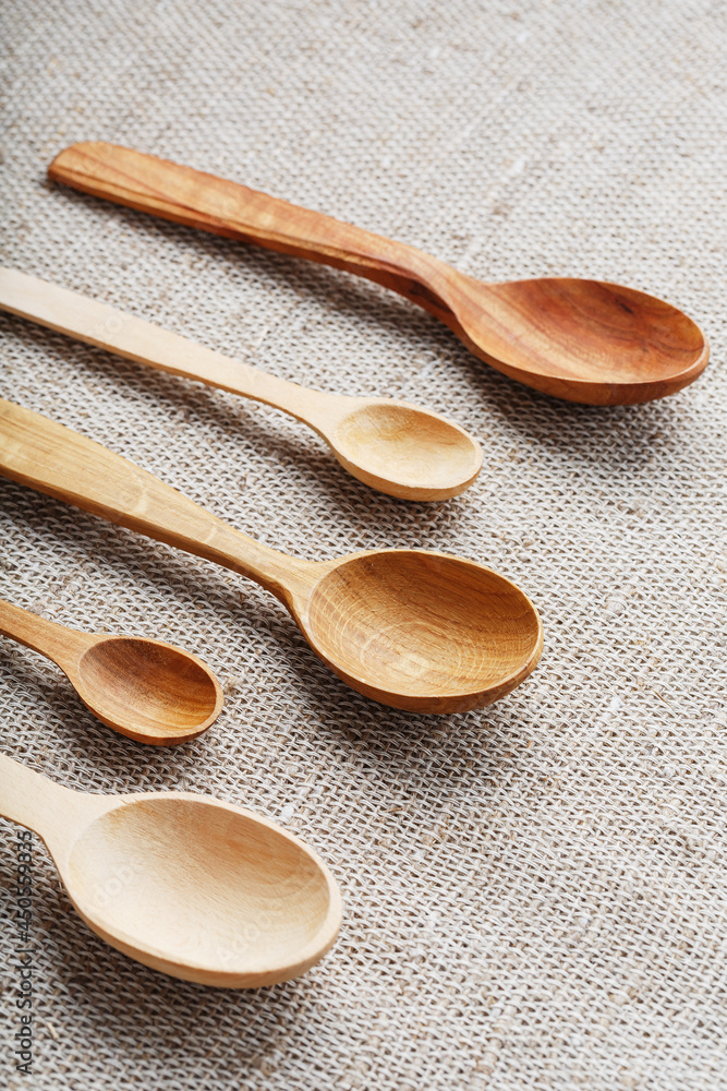 Wooden spoons made of natural wood on burlap fabric as a craft. Wooden spoons made of natural wood on burlap fabric as a craft.