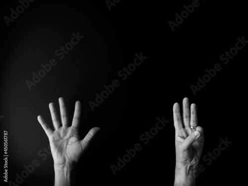 Black and white image of hand demonstrating sign language number eight against black background with empty copy space