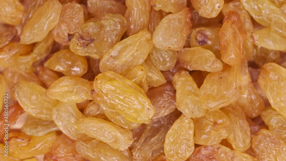 Top view of fresh yellow raisins. Raisins in slow motion on a moving platform