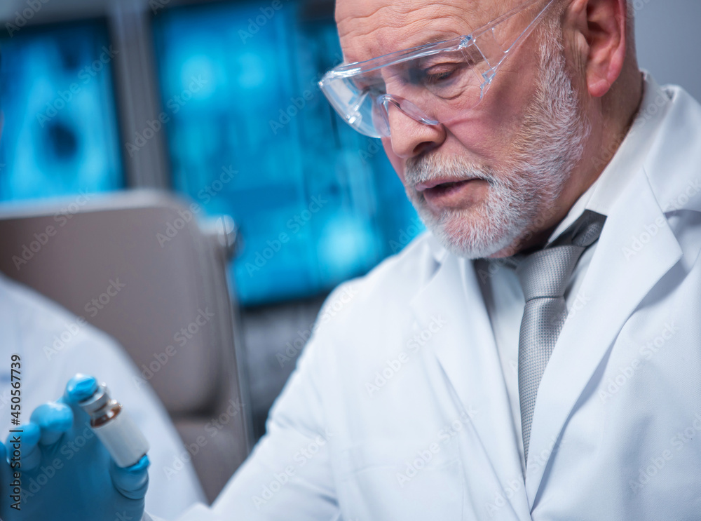 Professor works in a modern scientific laboratory using equipment and computer technologies. The scientist does research and develops new vaccines. Science and healthcare concept.