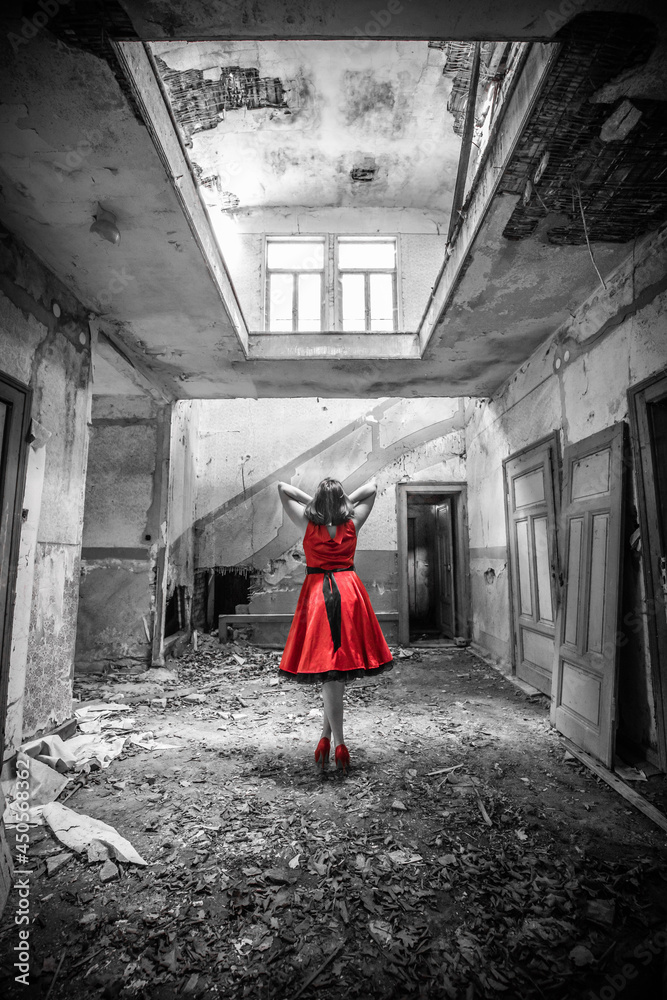Fototapeta premium Frau von hinten in einem verfallenen Haus mit roten Kleid als Color Key Lostplace