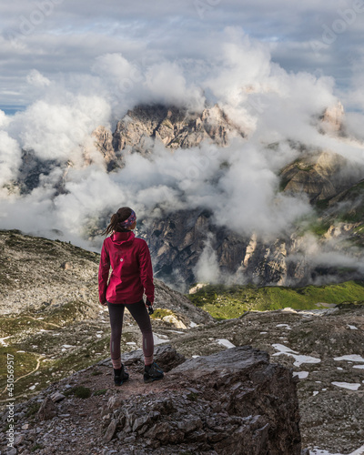 hiker on the top of mountain watching fog and clouds covering hills 