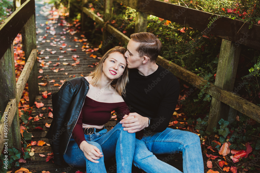 Young caucasian couple in love enjoys a moment of happiness in nature. The young man hugs his girlfriend on a romantic date in the fall park. Autumn mood. Selective focus. Copy space.