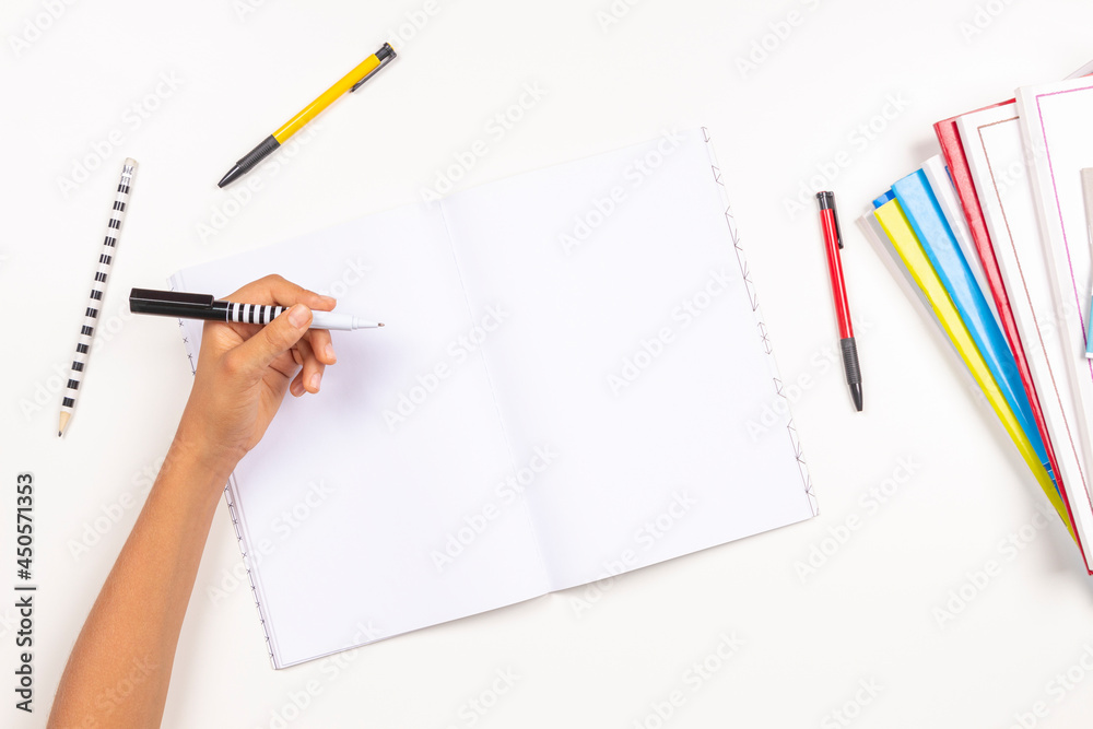 Kid hand holding pen in left hand and writing in open notebook, doing homework. Left Handers Day