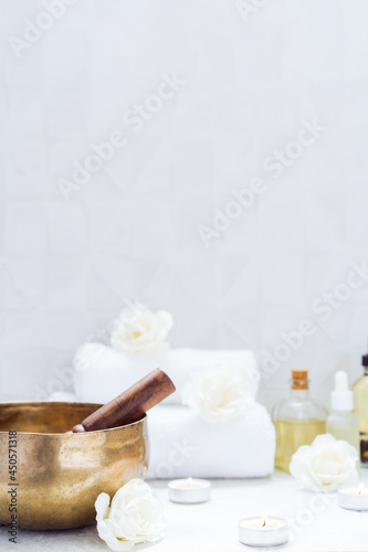 Spa and wellness massage setting with Tibetan singing bowl. Asian relaxing spa procedure with essential oils and sound healing therapy. Alternative medicine and body care. Vertical card. copy space.