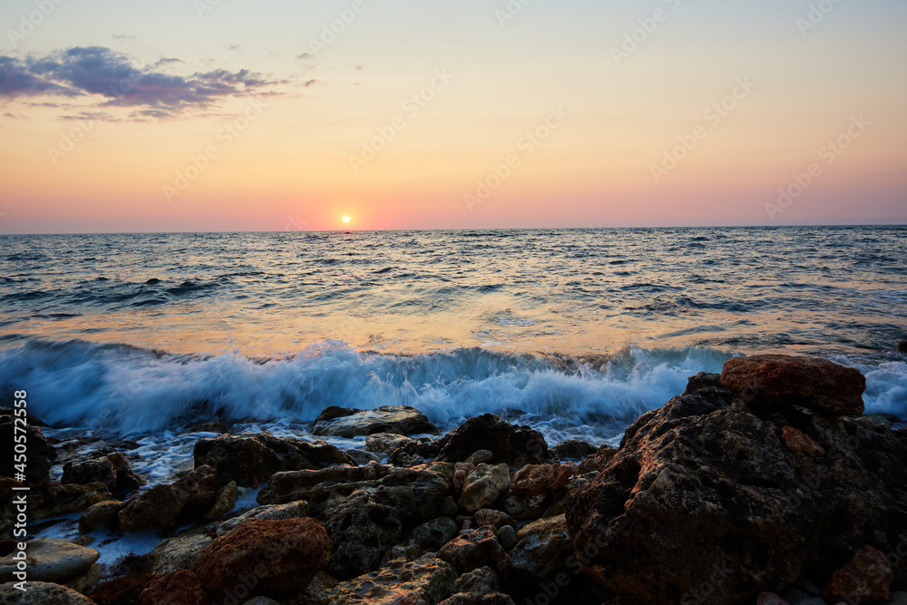 sunset on the rocky coast of the black sea with waves