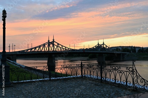 Urban landscape and a beautiful sunset in the evening on the river embankment with a bridge in the background. Copy space