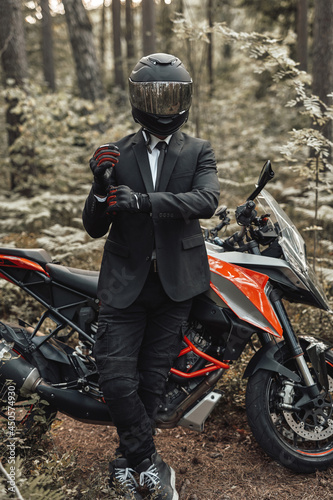 Businessman biker with gloves and helmet posing in forest
