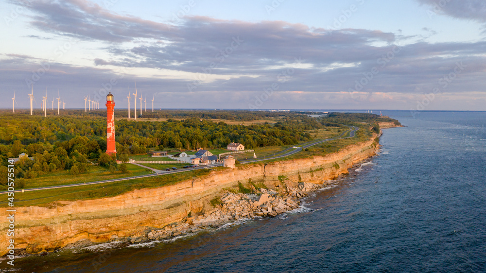 Sunset colored limestone cliff on Pakri peninsula, Estonia with the historic lighthouses and wind farm on the background Sunset colored limestone cliff on Pakri peninsula, Estonia with the historic lighthouses and wind farm on the background