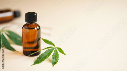 Medical Marijuana Cannabis oil extract in bottle green hemp leaves and glass test tubes beige background.Close-up glass bottles with CBD oil,THC tincture and hemp leaves.Cosmetics CBD oil.Copy space.