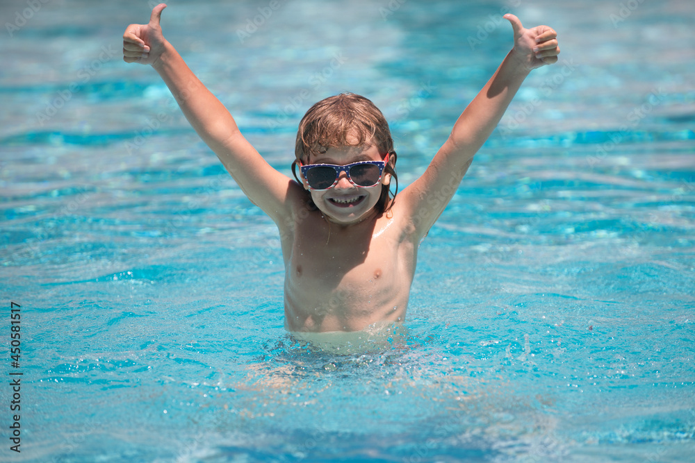 Cute child boy raised hands swim in swimming pool, summer water background with copy space. Funny kids face.