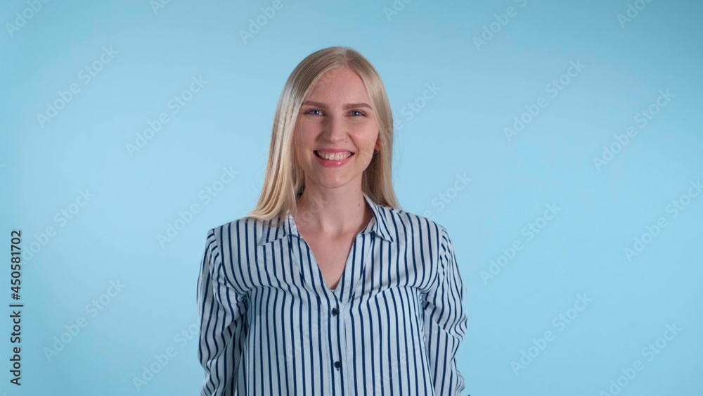 Pleasant-looking woman turning around and smiling to the camera. Blue background.