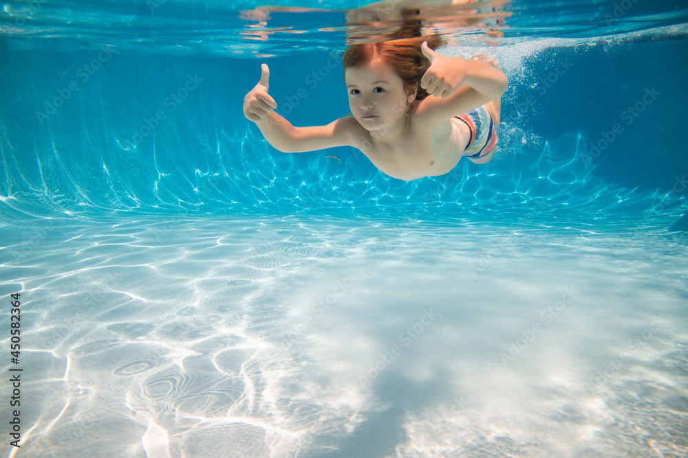 Happy kid swims in pool underwater, active kid swimming underwater, playing and having fun, Children water sport. Vacation and traveling with kids. Children play outdoors in summer water.