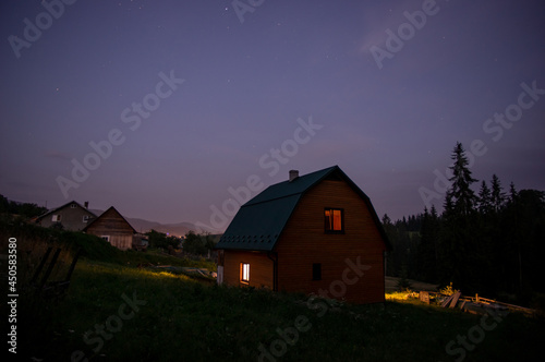 Evening landscape, wooden house in a village near the forest