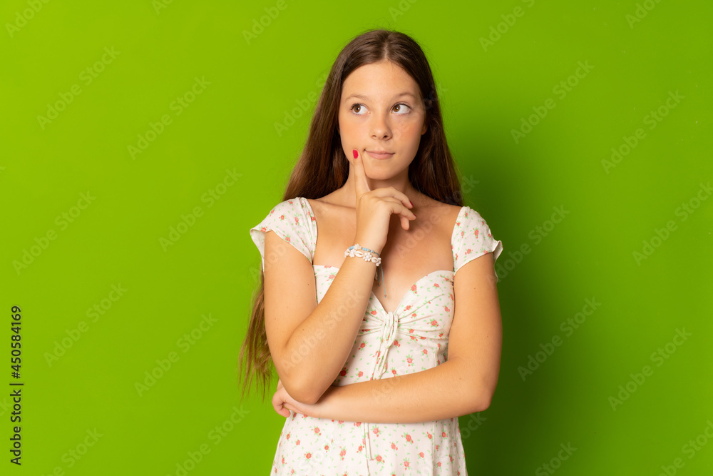 Pensive teenager girl in casual dress isolated over green background. Pensive teenager girl in casual dress isolated over green background.