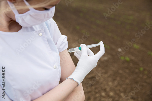 a nurse in a white coat and white gloves is giving a vaccine against the virus