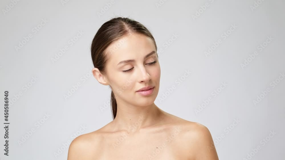 Beautiful Young Woman with Clean Fresh Skin standing over light grey background Beautiful Young Woman with Clean Fresh Skin standing over light grey background