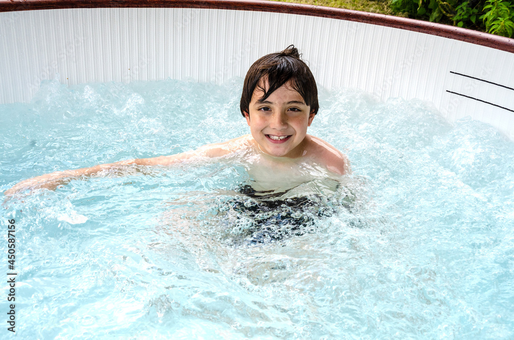 A young boy relaxed in a portable hot tub, rented for a few days and set up in the garden. A young boy relaxed in a portable hot tub, rented for a few days and set up in the garden.