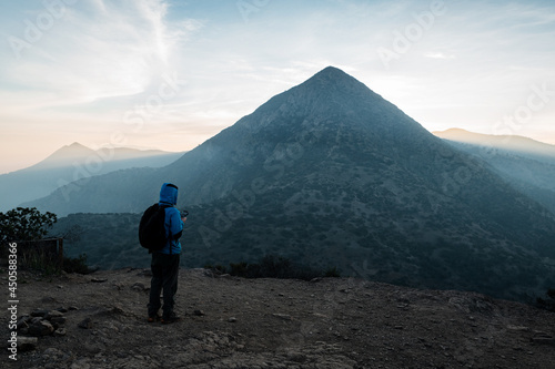 Young man in blue hoodie operating a drone in the open air with sunset in the background