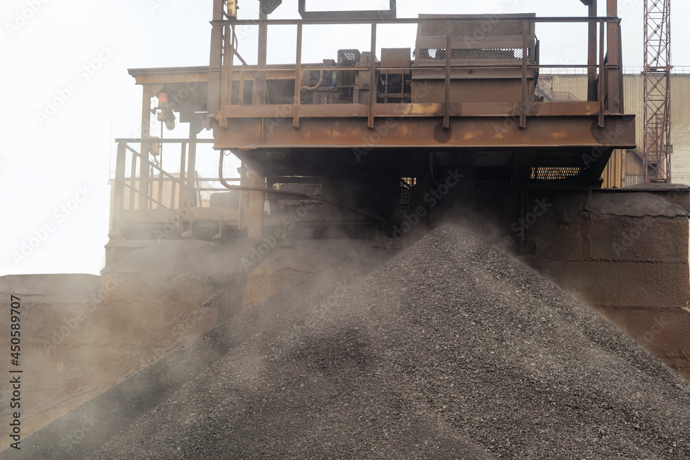 Iron ore pellets are piled from the conveyor belt into a heap. Falling