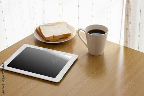 Fototapeta Naklejka Na Ścianę i Meble -  朝食を食べながら、タブレット端末を使う、イメージ