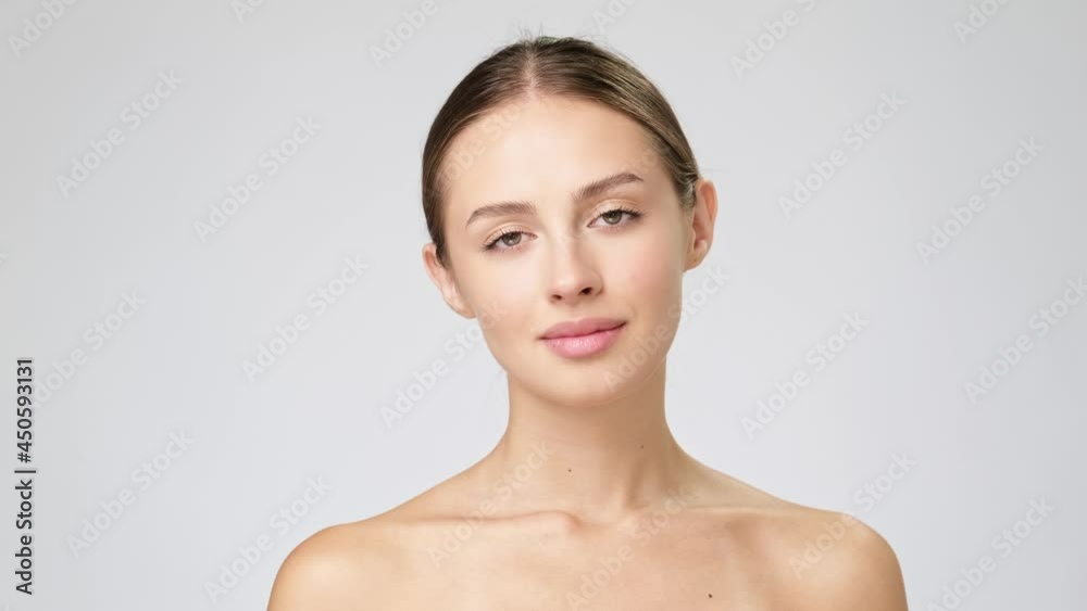 Beautiful Young Woman with Clean Fresh Skin standing over light grey background Beautiful Young Woman with Clean Fresh Skin standing over light grey background