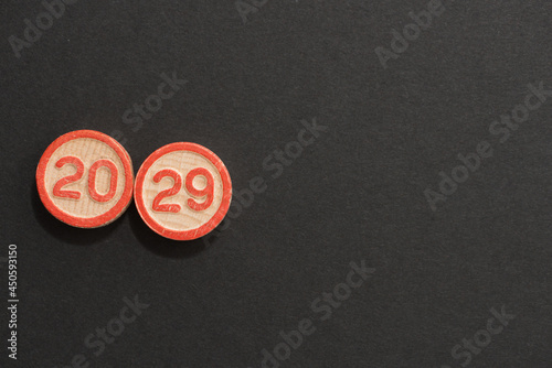 solid wood discs with the numbers 20 and 29 etched on both sides and highlighted in red-oranged and arranged on black background photo
