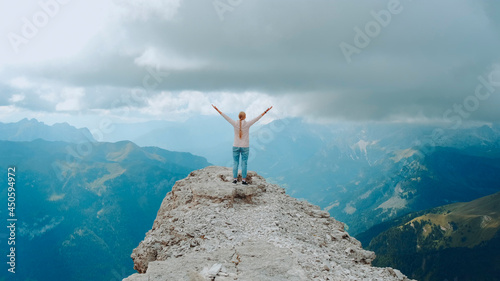 Happy free woman with outstretched hands on the top on the rock. Enjoying nature and feeling free.