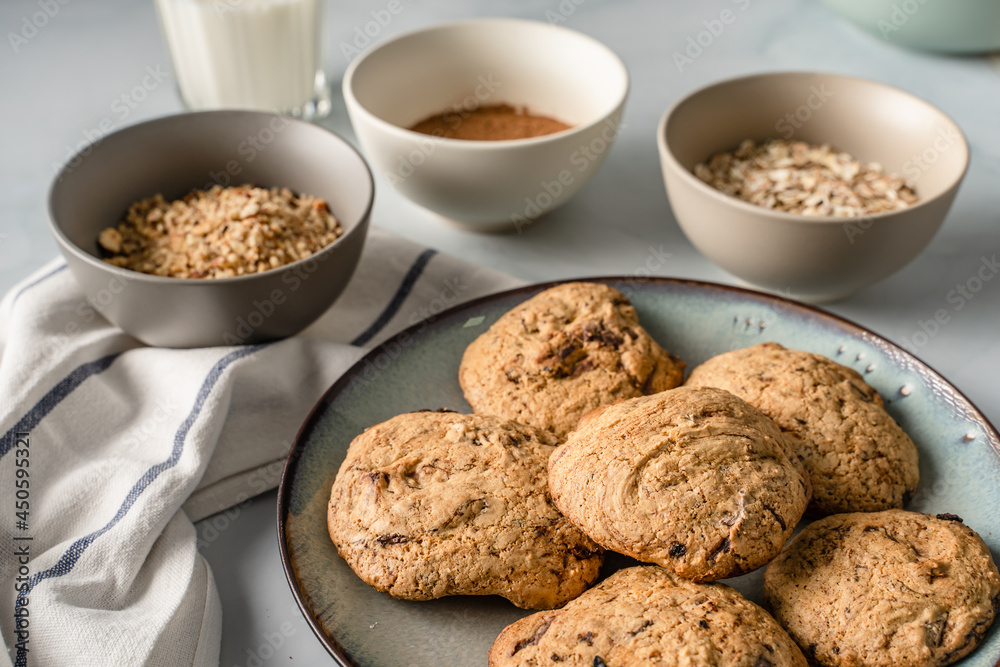 Close up front view on crunchy oatmeal chip cookies fresh baked biscuits with chocolate and cocoa in a plate on the table and ingredients beside homemade food concept Close up front view on crunchy oatmeal chip cookies fresh baked biscuits with chocolate and cocoa in a plate on the table and ingredients beside homemade food concept