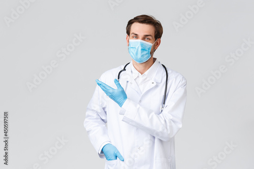 Hospital, healthcare workers, covid-19 treatment concept. Smiling professional doctor introduce new treatment, application or medical pills, promo of vitamins, pointing upper left corner