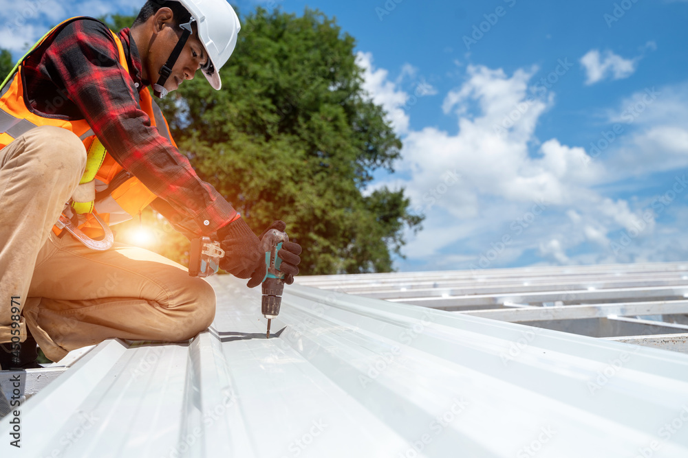 Roofer working at metal profile roof installation,Roofing tools,Electric drill used on new roofs.
