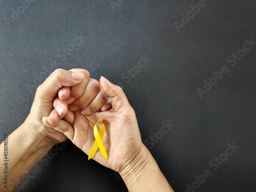 Celebration Day Concept - yellow ribbon on palm background. Symbolize the world suicide prevention day. Stock photo. photo