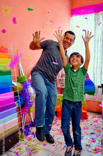 Happy and cheerful latino Mexican father and son piñata makers together cheering and dancing