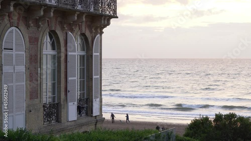 People Walking At The Beach Outside Hotel des Roches Noires In Trouville, France On A Sunset. static