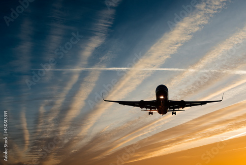 Landing airplane at colorful sunrise with with beams of sun lights. Concept o...