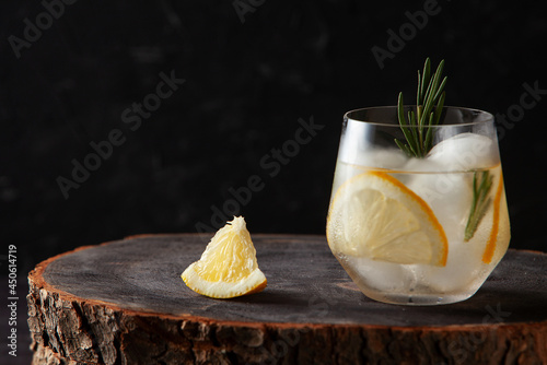 refreshing drink with lemon rosemary and ice on dark wooden background photo