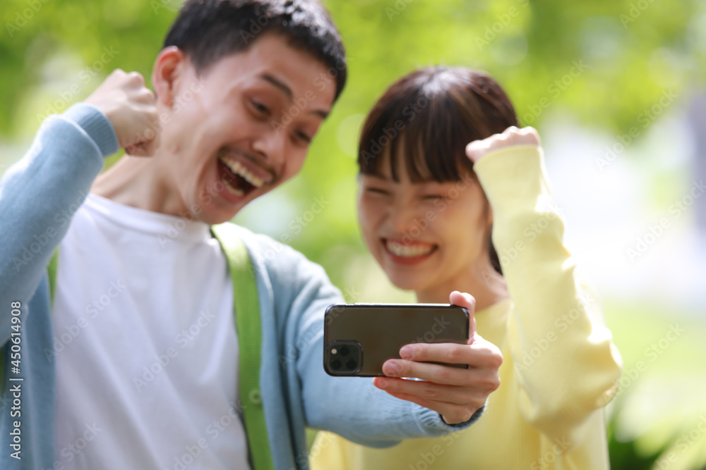 スマートフォンでスポーツ観戦するカップル スマートフォンでスポーツ観戦するカップル