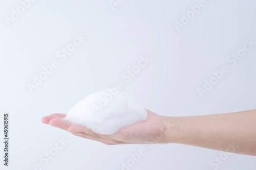 white soapy foam bubbles texture on hand.  cleaning and wash essence facial cleanser background concept
