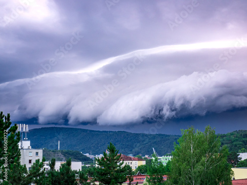 A massive Shelf cloud, Arcus cloud, is slowly rolling over the hill above the city Usti nad Labem photo