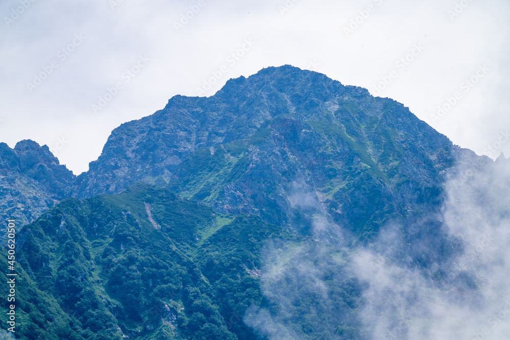 Fototapeta premium 富山県中新川郡上市町の中山から立山の剱岳を望む登山をしている風景 A view of mountain climbing with a view of Tsurugidake in Tateyama from Nakayama in Kamiichi Town, Nakashinagawa County, Toyama Prefecture.